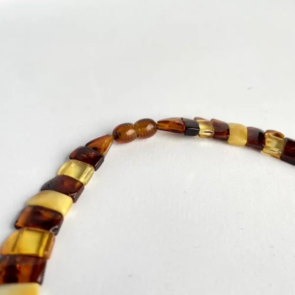 Elegant amber bead necklace showcasing unique shades, shapes, and natural beauty against a white backdrop.