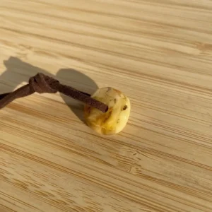 Beautiful amber pendant on suede cord against warm wood, showcasing natural elegance and craftsmanship.