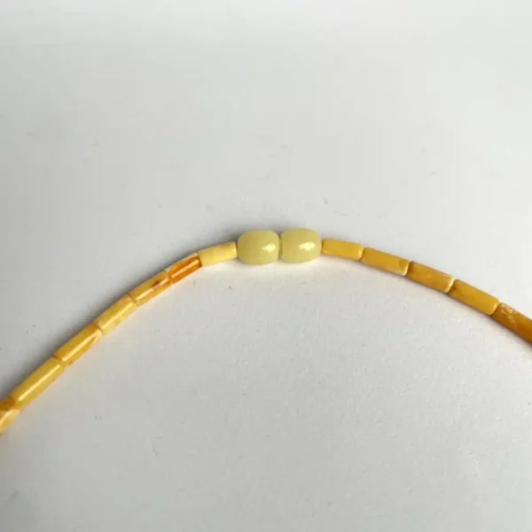 Elegant yellow beaded amber necklace with varied shapes and glossy focal beads, showcasing artisan craftsmanship.