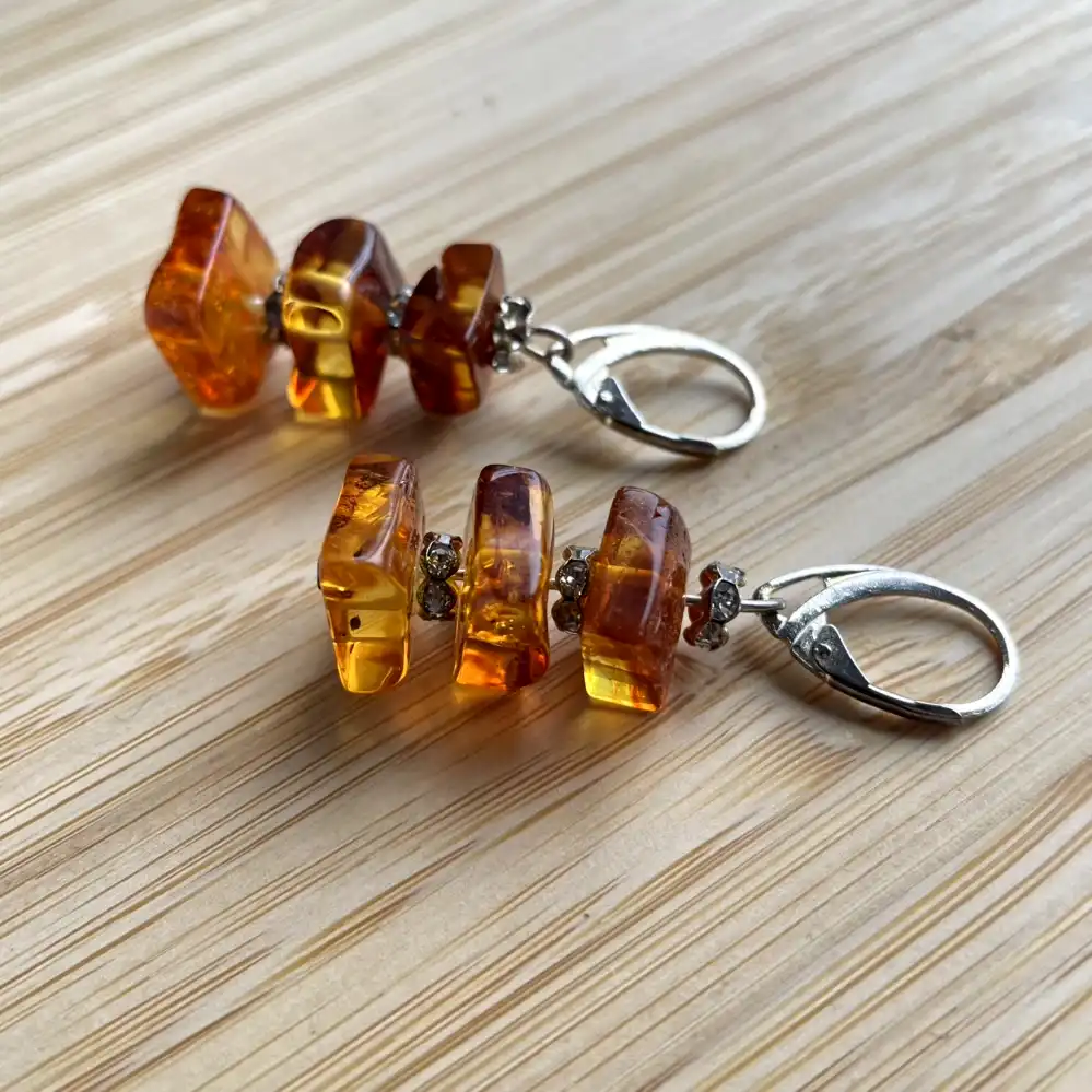 Elegant amber bead earrings with silver clasp, showcasing warm hues and organic design.