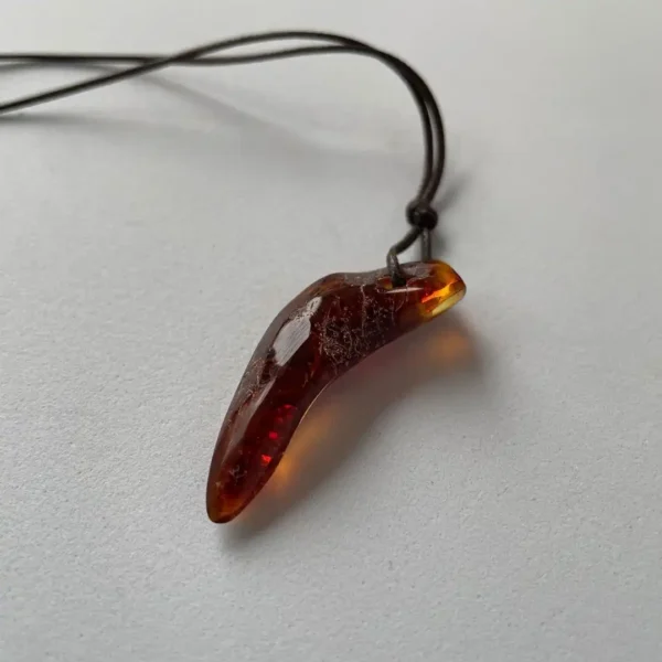 Unique amber fang pendant on a sleek cord, showcasing natural beauty and artisanal craftsmanship.