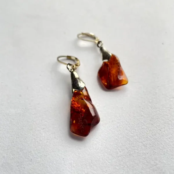 Elegant amber earrings with unique shape and polished metal clasps, perfect for any occasion.