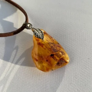 Amber pendant with silver leaf bail on suede cord, highlighting natural elegance and craftsmanship.