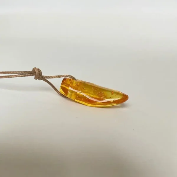 Elegant amber pendant in golden hues on a rustic cord, showcasing natures beauty.