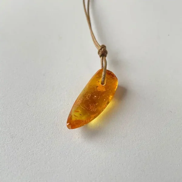 Natural amber teardrop pendant necklace on leather cord, showcasing warm hues and organic beauty.