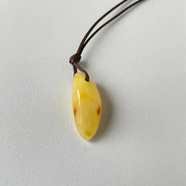 Elegant amber teardrop pendant on brown cord, showcasing organic beauty and artisan craftsmanship.