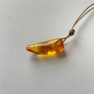 Elegant amber teardrop pendant on natural cord, showcasing warm hues and unique inclusions.