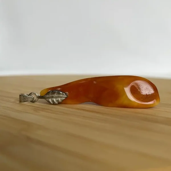 Elegant amber teardrop pendant with silver leaf detail, perfect for versatile jewelry styles.