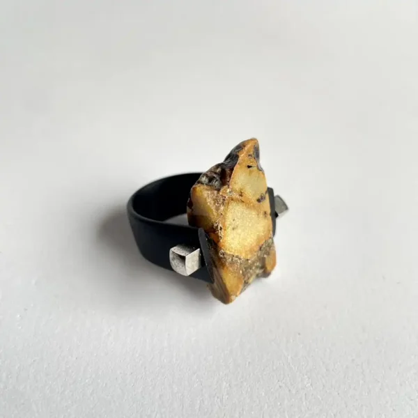 Unique irregular amber stone ring with earthy tones and modern black band accents.
