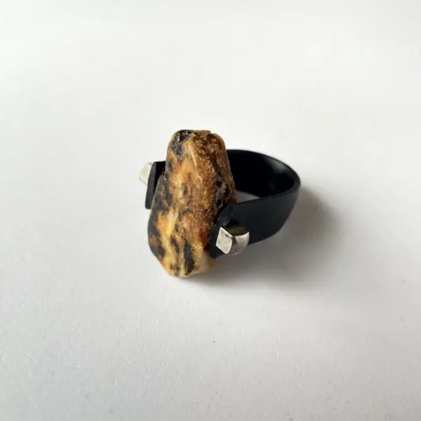 Unique natural amber stone ring with black band and metallic accents, perfect for modern jewelry lovers.