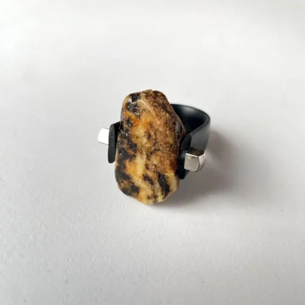 Unique natural amber stone ring with earthy tones and sleek black band, perfect for artistic jewelry lovers.