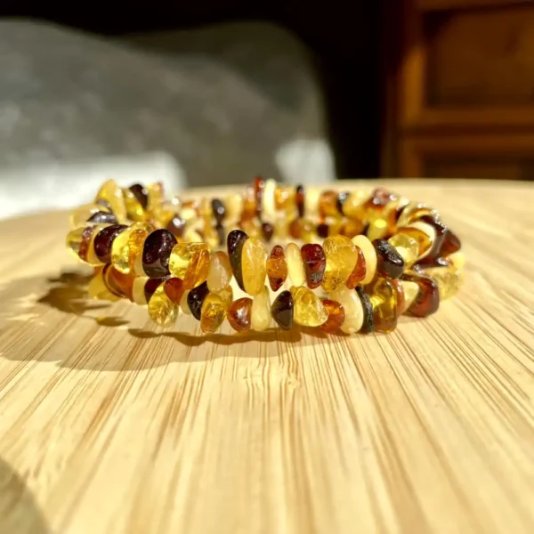 Polished amber bead bracelet featuring vibrant colors and unique shapes on a wooden background.