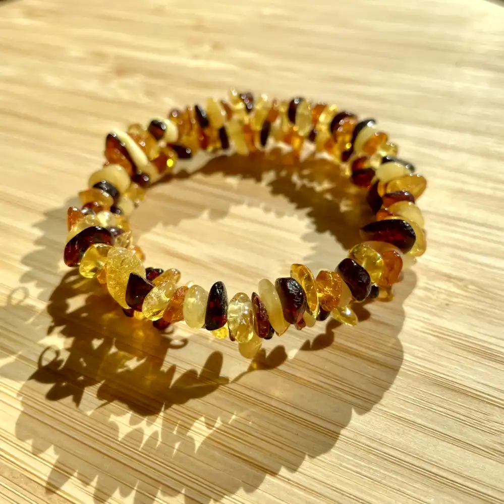 Beautiful amber bracelet with colorful beads on a natural wood background.