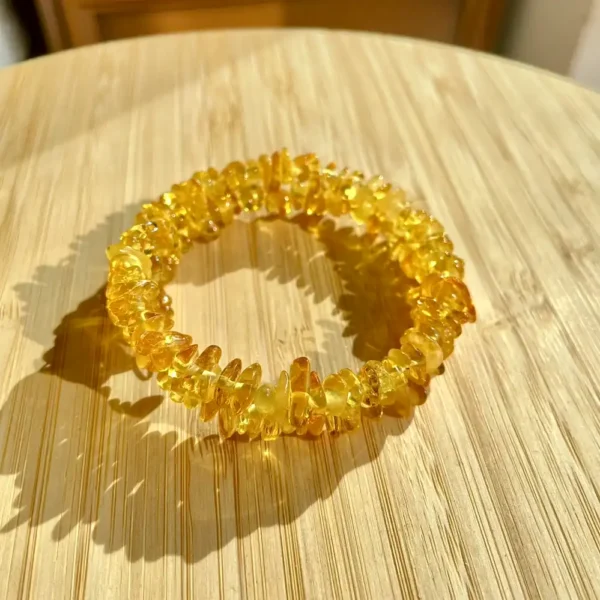 Vibrant amber resin bracelet on a natural bamboo surface, showcasing unique artisanal charm.