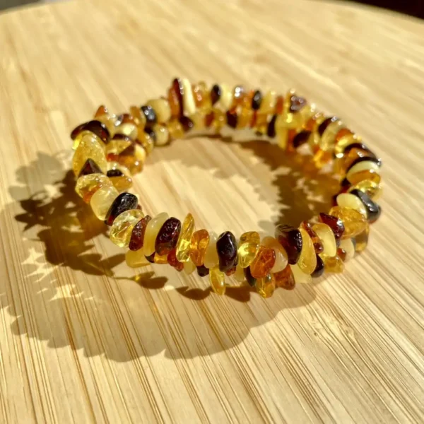 Beautiful polished amber bracelet with varied hues on a light wooden surface.