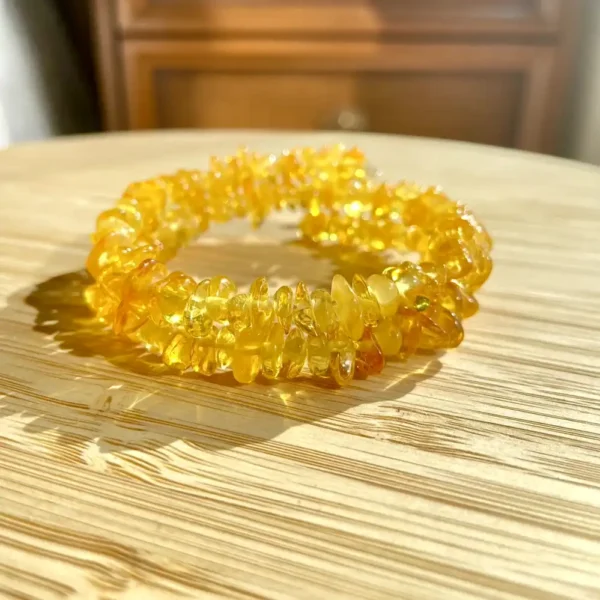 Vibrant yellow amber bracelet on wooden surface, showcasing natural beauty and warm luminosity.
