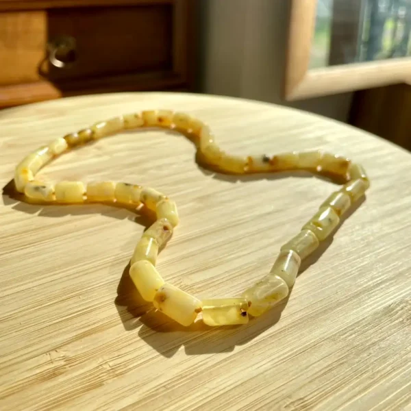 Amber necklace showcasing natural beads on a textured wooden surface, reflecting light beautifully.