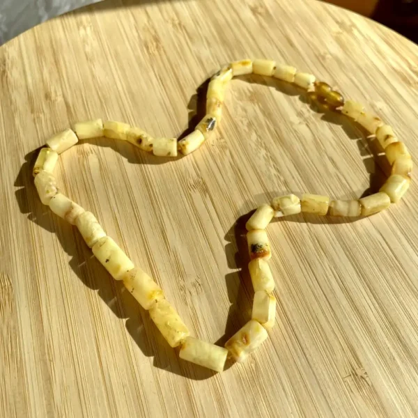 Elegant light yellow heart necklace on wooden surface, showcasing handmade craftsmanship and natural beauty.
