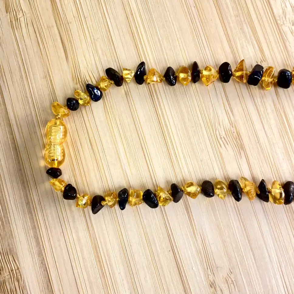 Elegant amber teething necklace on a wooden background, showcasing natural beauty and artistry.