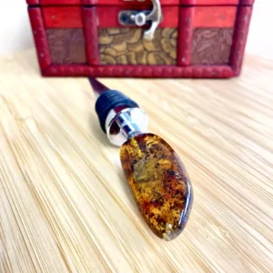 Elegant amber bottle stopper with silver-plated accents, displayed on a wooden surface.