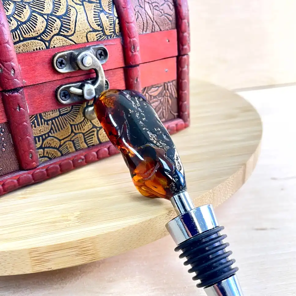 Elegant amber bottle stopper with intricate antique wooden chest backdrop, showcasing exquisite craftsmanship.