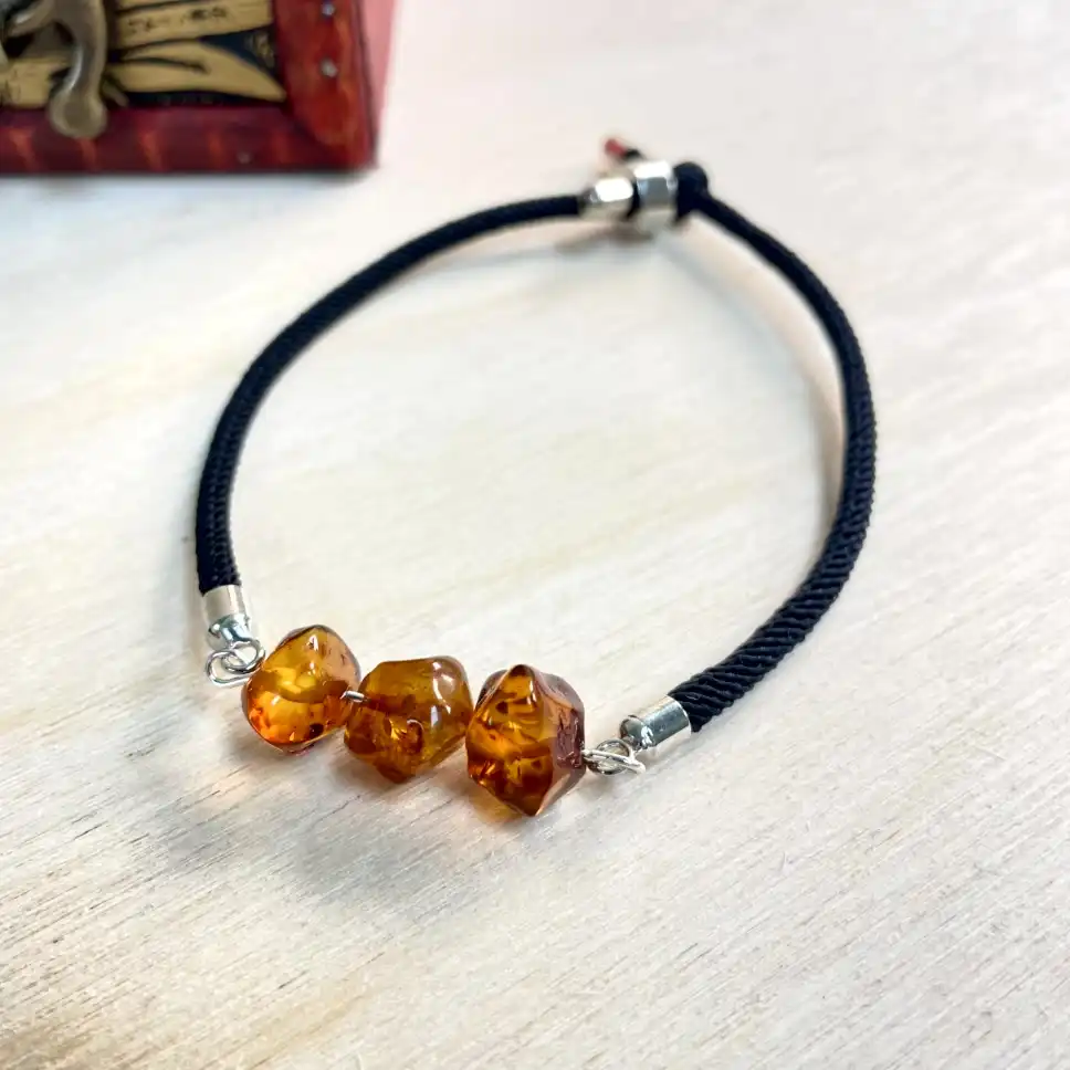 Stylish amber bracelet on a black cord, perfect for casual or formal occasions.