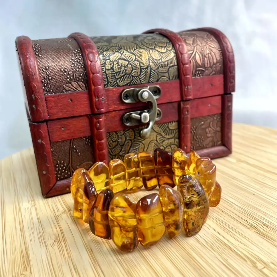 Amber bracelet beside vintage wooden chest, showcasing craftsmanship and elegance in a captivating scene.
