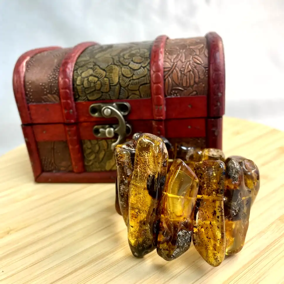 Amber bracelet displayed beside an ornate treasure chest, showcasing natural beauty and vintage charm.