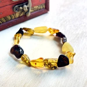 Vibrant amber nugget bracelet on a wooden surface, showcasing unique beads and natural beauty.