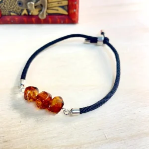 Elegant amber bracelet on black braided cord, featuring vibrant beads and silver-plated clasps.