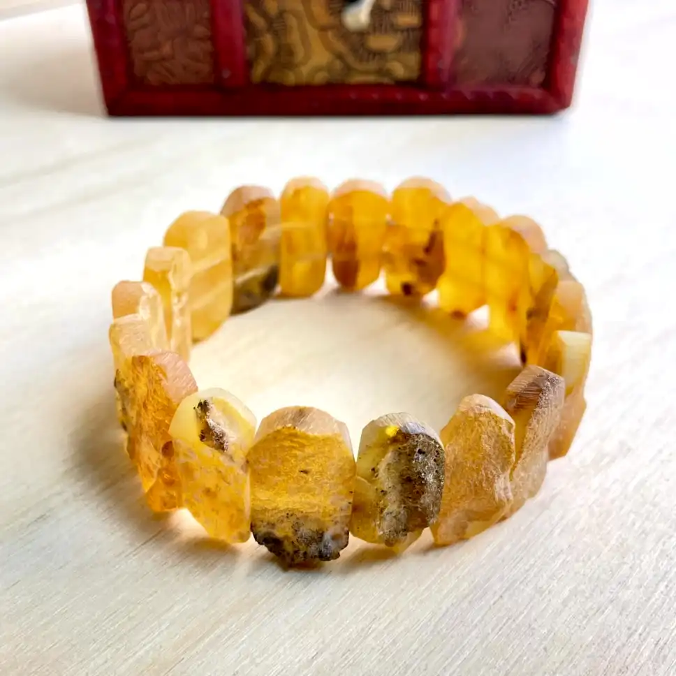 Natural Amber Bracelet with Medium Stones with unique beads on a wooden surface, showcasing rich golden hues.