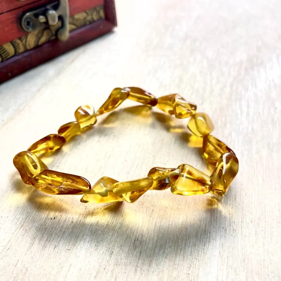 Stunning amber nugget bracelet with unique beads resting on natural wood, showcased in an artisanal red box.