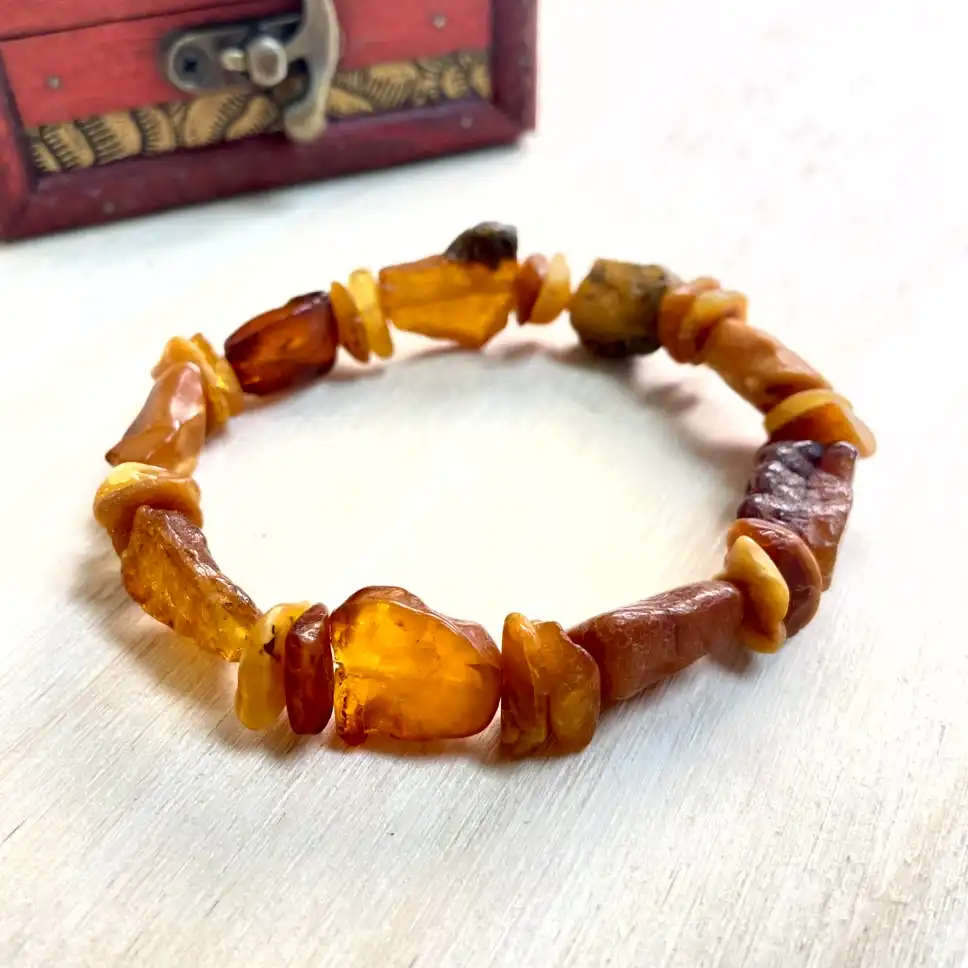 Amber nugget bracelet with polished gemstones displayed beside a decorative red wooden box.