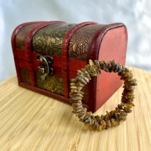 Charming amber gemstone bracelet displayed in front of an ornate vintage treasure chest.