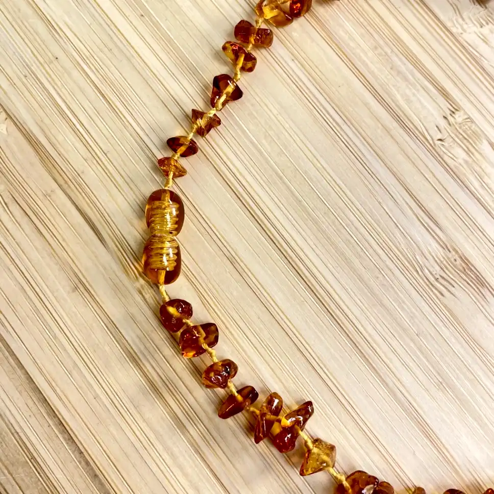 Stunning amber necklace beads showcasing rich orange hues against a light wooden background.