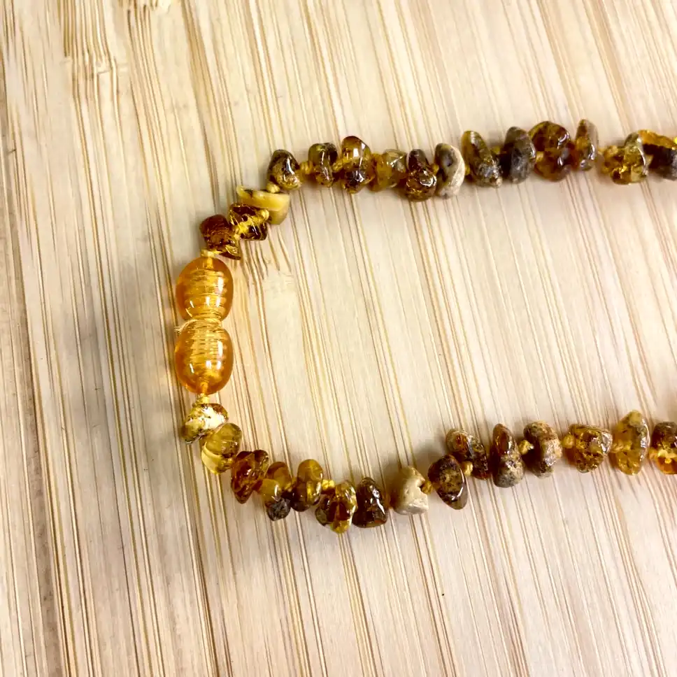 Elegant amber necklace with unique beads on a textured wooden surface.