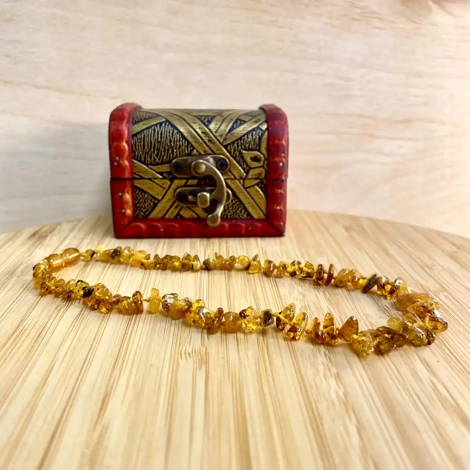 Elegant amber necklace displayed on a wooden surface, accompanied by a decorative chest.