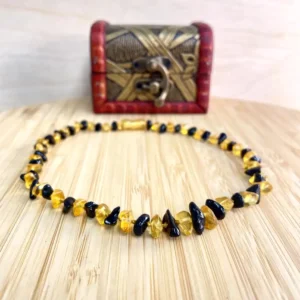 Stunning amber and black bead necklace displayed on wood, accompanied by an elegant decorative box.