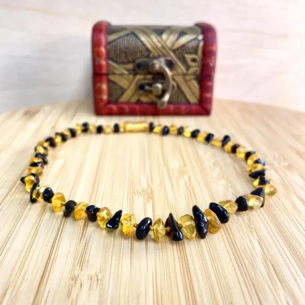 Stunning amber and black bead necklace displayed on wood, accompanied by an elegant decorative box.