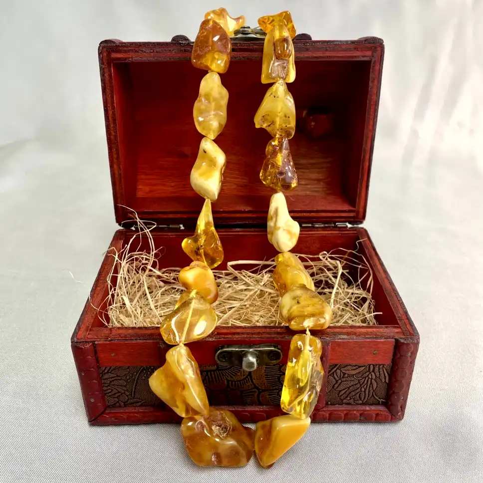 Antique wooden chest showcasing a handcrafted amber necklace with rich, warm hues.
