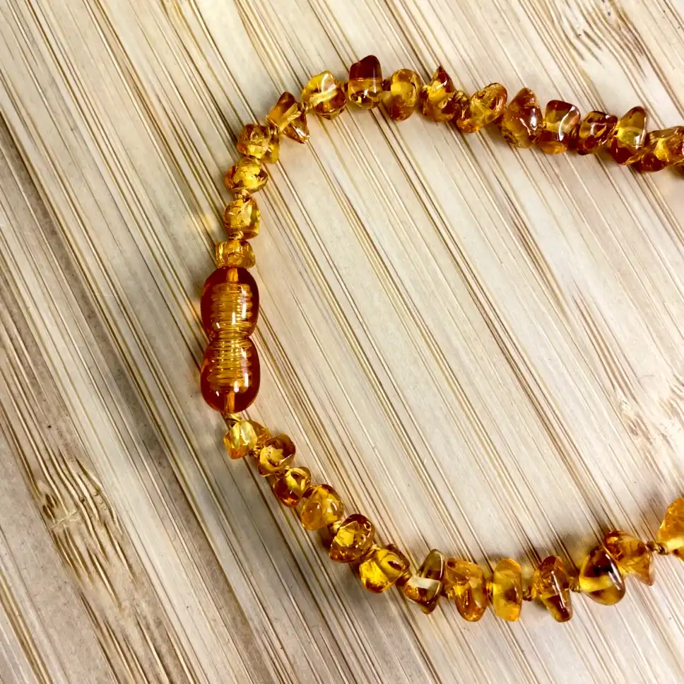 Elegant amber necklace with golden beads, showcasing unique shapes and textures on a wooden surface.