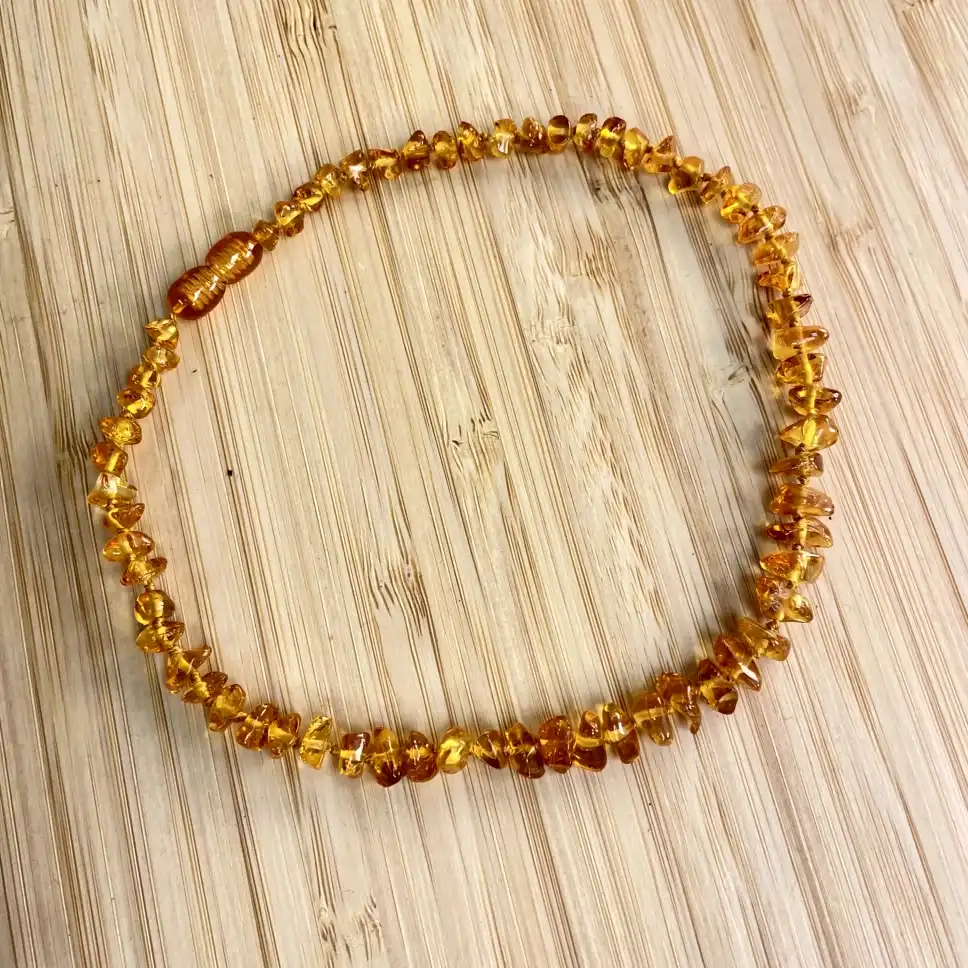 Elegant amber necklace on textured wood background, showcasing natural beads and warm hues.