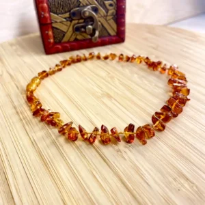 Amber necklace resting on wood, showcasing exquisite beads and a vintage wooden box.
