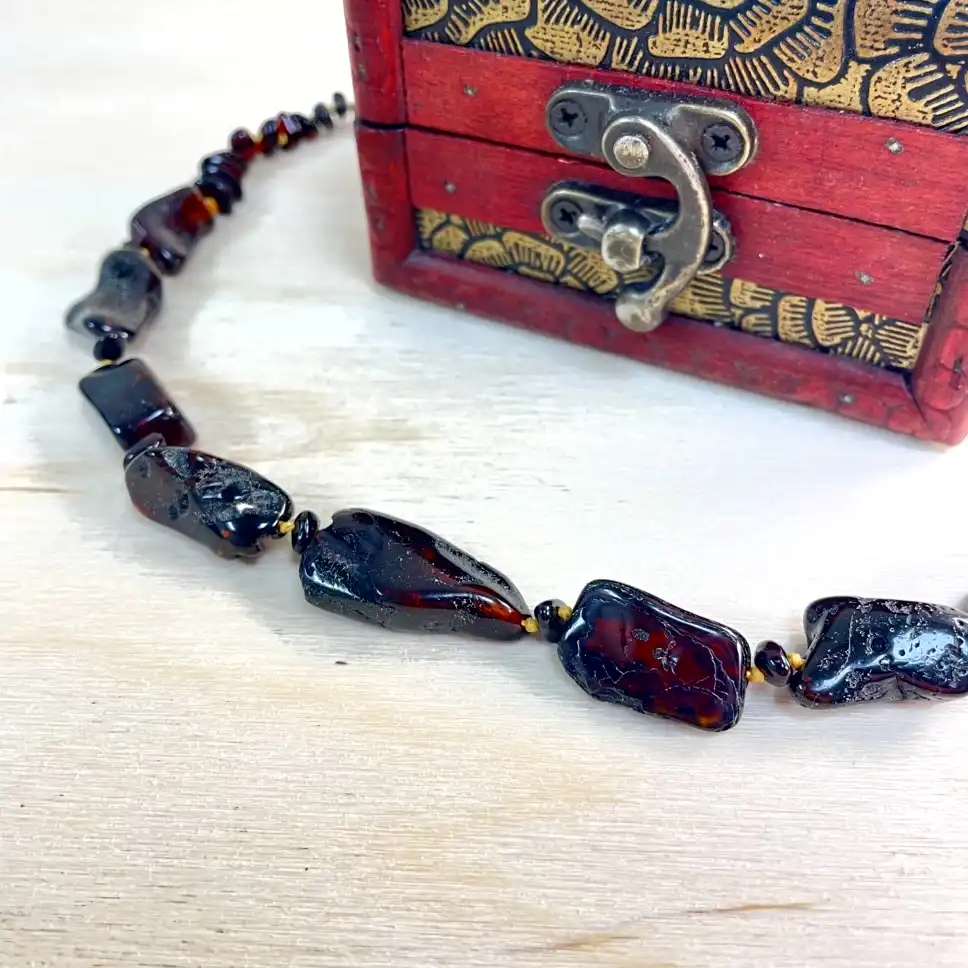 Elegant amber necklace with decorative wooden box, showcasing unique handcrafted jewelry and rich hues.