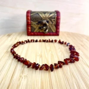 Elegant amber necklace on a wooden surface, paired with a decorative cultural box.