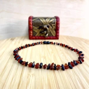 Elegant amber teething necklace displayed on bamboo platform with ornate decorative chest.