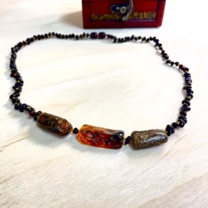 Vibrant amber necklace with medium stones showcased on a wooden surface, complete with an ornate wooden box.