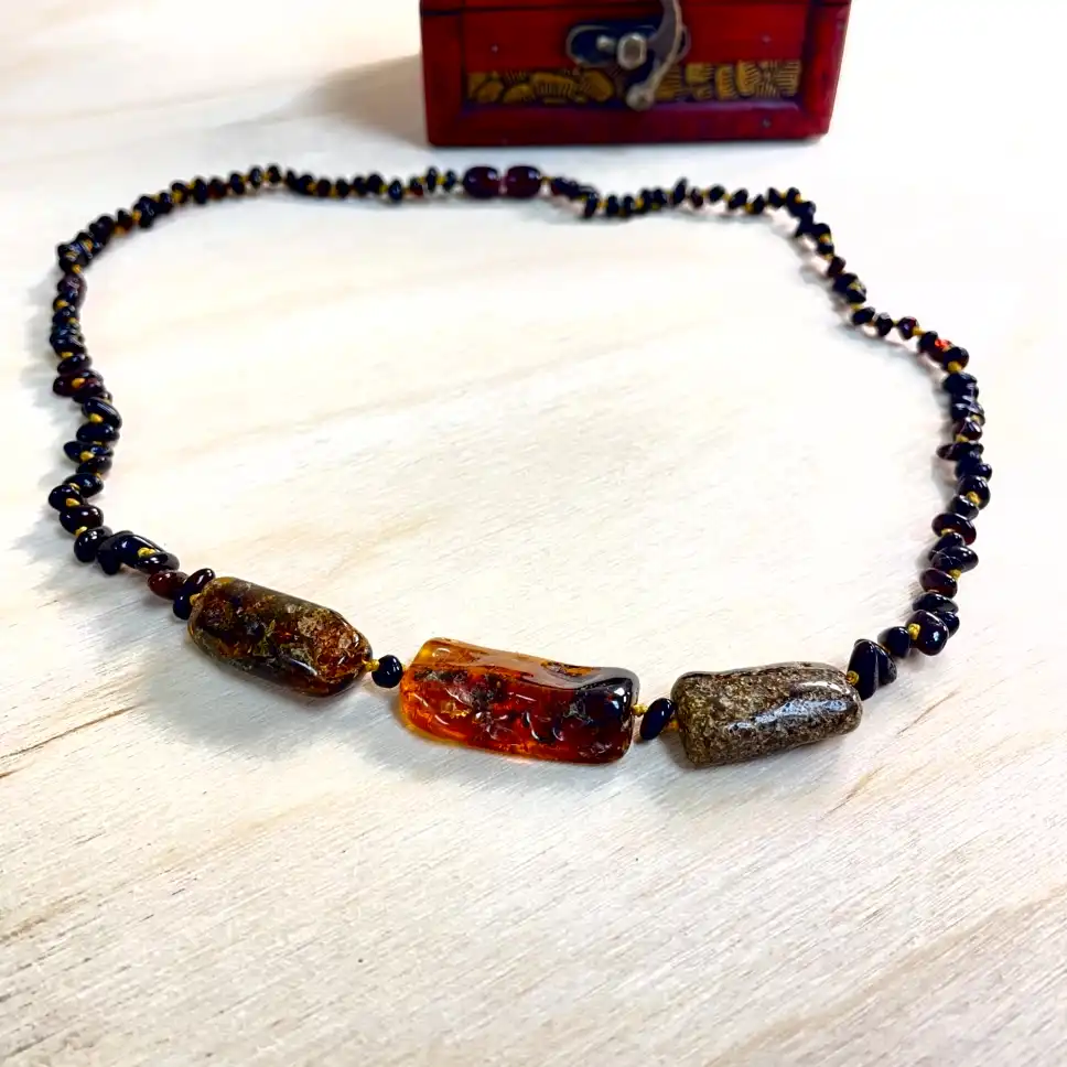 Vibrant amber necklace with medium stones showcased on a wooden surface, complete with an ornate wooden box.