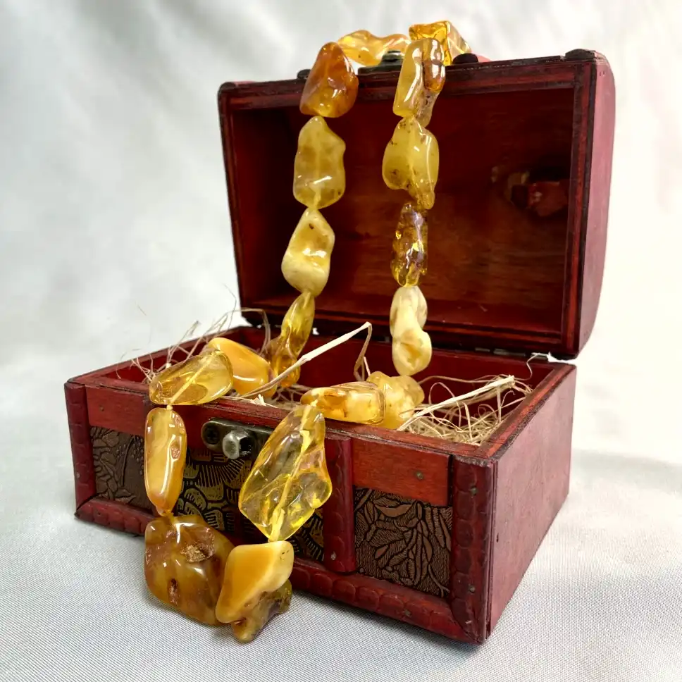 Antique red wooden box showcasing a stunning amber necklace, perfect for vintage jewelry lovers.