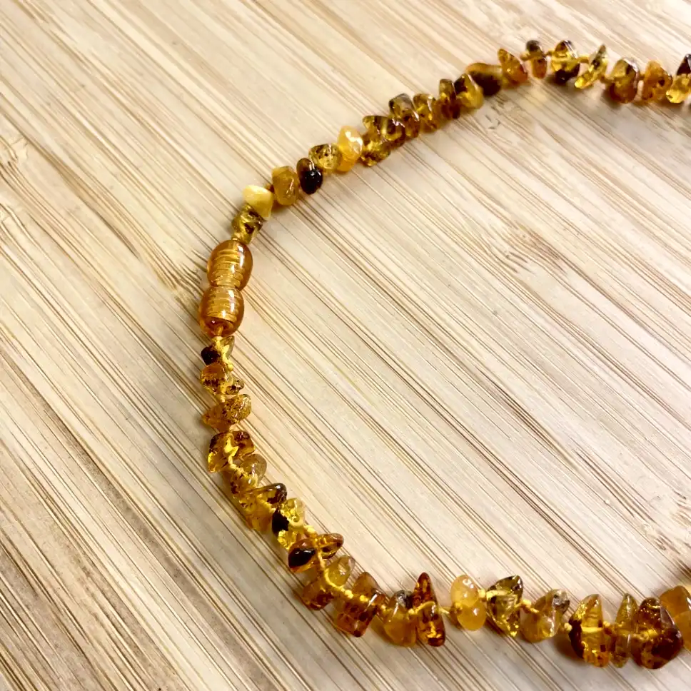 Elegant amber necklace featuring natural beads in warm golden tones on a light wooden background.